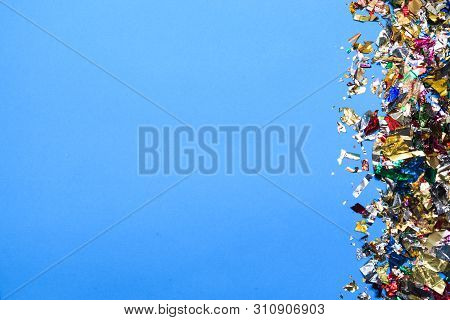 Festive Party Or Carnival Border Of Colored, Shiny Serpentines And Confetti On Light Blue Background