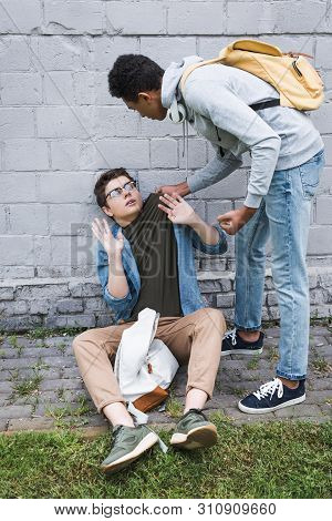 Aggressive And Brunette African American Boy Holding T-shirt Of Frightened Boy In Glasses