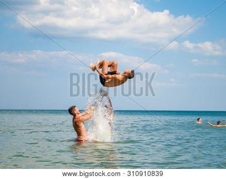 Odesa Rgn. Ukraine, July 16, 2018: Teenagers Bathing In The Sea Doing Backflips At Summer Camp