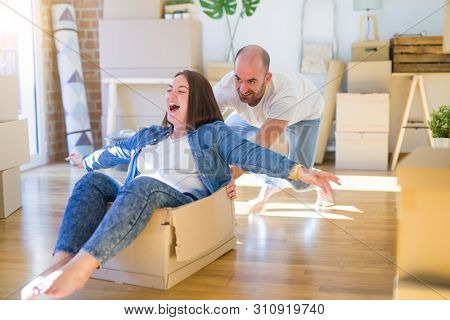 Funny and crazy couple having fun riding a cardboad box as a car, smiling happy and lauging at new home