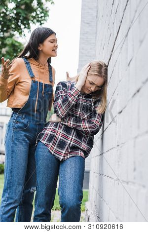 Aggressive And Brunette Teenager Yelling At Blonde And Scared Teenager
