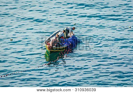 Cala Iris, Morocco - October 18, 2013. Fishermen On Boat Using Net Near Bay In Moroccan Coast Of Med