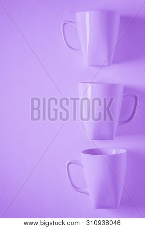 3 Purple Coffee Mugs On Purplish Background In A Vertical Row, Empty Copy Space