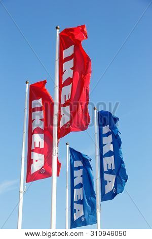 Huddinge, Sweden - July 11, 2019: A Group Of Four Ikea Flags And Flagpoles Against The Blue Clear Sk