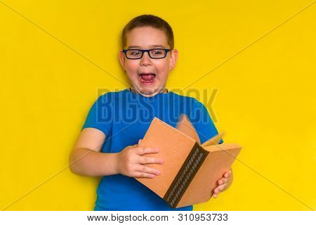 Funny Little Boy With Glasses And Blue T-shirt Holding A Book And Screaming With Fear, Lazy Student 