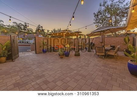 Dining And Seating Area On A Stone Brick Patio Illuminated By String Lights