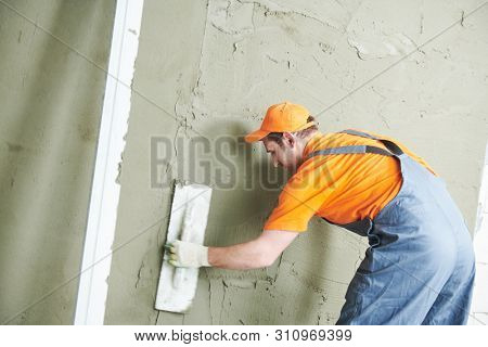Renovation at home. Plasterer smoothing plaster on wall.