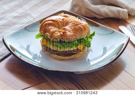 Sausage Egg And Cheese On Flaky French Croissant Roll With Romaine Lettuce