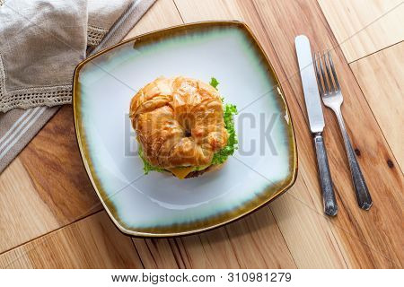 Sausage Egg And Cheese On Flaky French Croissant Roll With Romaine Lettuce