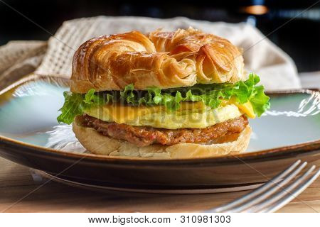 Sausage Egg And Cheese On Flaky French Croissant Roll With Romaine Lettuce
