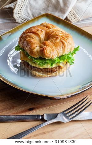 Sausage Egg And Cheese On Flaky French Croissant Roll With Romaine Lettuce
