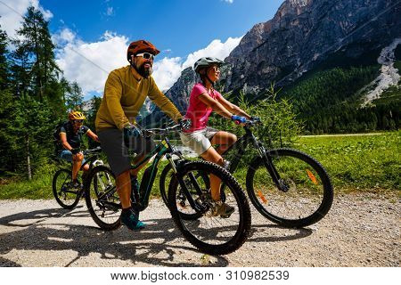 Tourist cycling in Cortina d'Ampezzo, stunning rocky mountains on the background. Family riding MTB enduro flow trail. South Tyrol province of Italy, Dolomites.