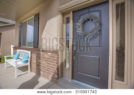 Porch And Front Door With Wreath And Sidelights Viewed On A Sunny Day
