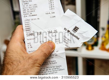 Frankfurt, Germany - Mar 16, 2019: Man Hand Holding Edeka Food Supermarket Printed Receipt With Food