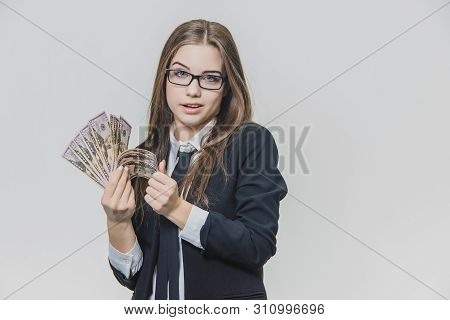 Concentrated Young Business Woman Is Counting A Pile Of Money, Isolated On White Background. Girl Is