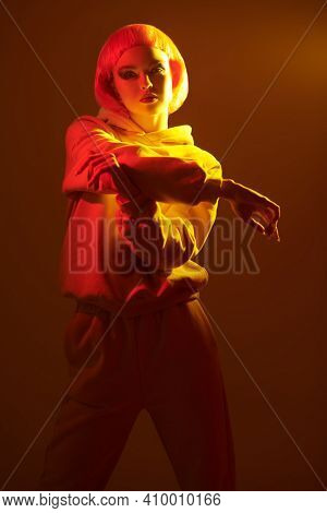 Contemporary girl with bright makeup and  wig  poses in mixed color light. Sport chic fashion. Youth fashion and beauty trends. 