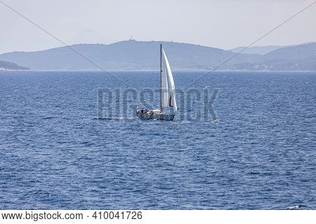 A Single White Sailing Boat In The Open Sea.