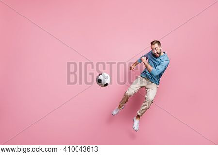 Full Length Photo Of Strong Purposeful Young Man Dressed Blue Sweater Jumping High Kick Football Bal