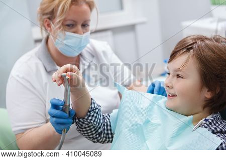 Cheerful Young Boy Laughing, Touching Dental Tools Of His Dentist