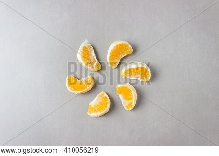 Mandarin Slices Laid Out Around In The Shape Of Flower Petals Or Sunlight On A Gray Background