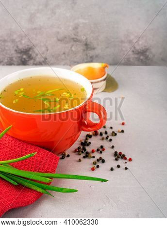 Hot Homemade Chicken Broth With Collagen And Amino Acids In Red Bowl With Red Napkin And Green Onion