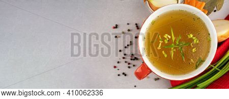 Hot Homemade Beef Bone Broth With Collagen And Amino Acids In Red Bowl With Red Napkin And Green Oni