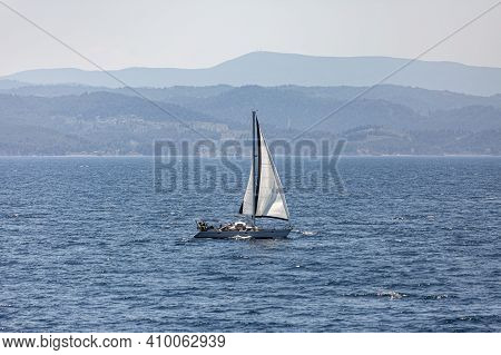 A Single White Sailing Boat In The Open Sea.
