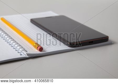 Open Notebook, Pencil And Mobile Phone Laid Out On White Isolated Background