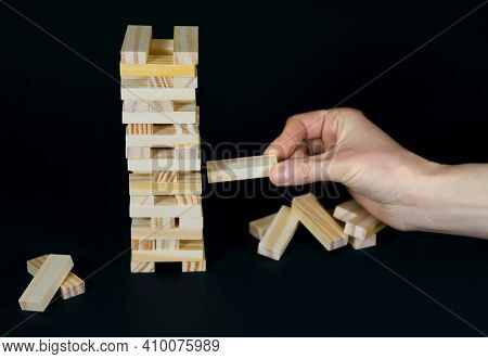 Wooden Board Game On A Black Background. People Play A Game Of Chance In Which Balance And Settlemen
