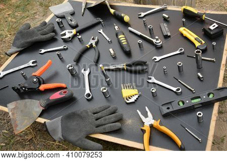 Handyman Tool Kit On Black Wooden Table. Many Wrenches And Screwdrivers, Pilers And Other Tools For 