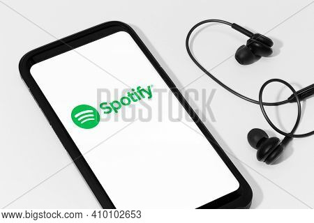 Galicia, Spain; February 25, 2021: Spotify Logo On Smart Phone Screen And Earphones On White Backgro