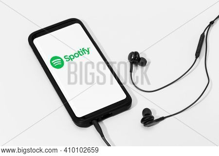 Galicia, Spain; February 25, 2021: Spotify Logo On Smart Phone Screen And Earphones On White Backgro
