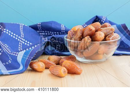 Pileof dried sweet deglet nour date fruites in translucent bowl and dark blue napkin.Organic vegetar