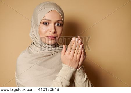 Confident Portrait Of Young Serene Muslim Woman Wearing Beige Hijab And Traditional Clothes Praying 