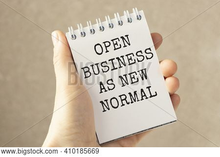Notepad With The Words Open Business As New Normal In Hand.adapting To New Life Or Business Post-loc
