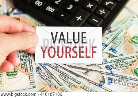 A Hand Holds A Sign With The Inscription - Value Yourself On The Background Of Banknotes And A Calcu