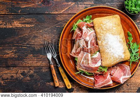 Spanish Bocadillo De Jamon, Serrano Ham Sandwich On Ciabatta Bread With Arugula. Dark Wooden Backgro