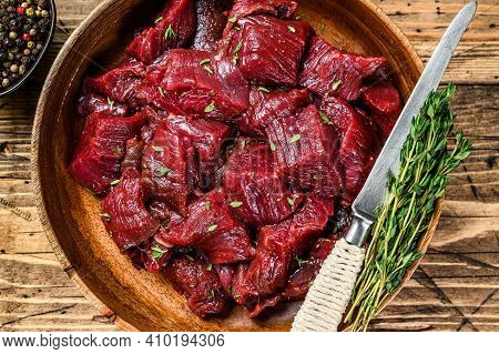 Raw Cut Wild Venison Meat For A Goulash In A Wooden Plate. Wooden Background. Top View