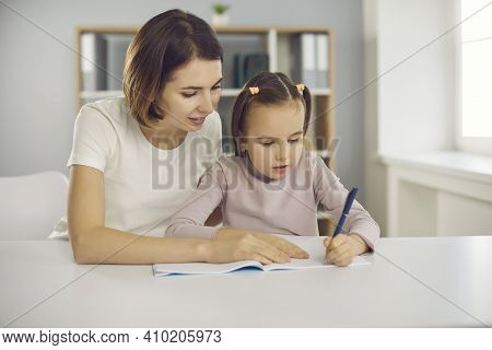 Small Concentraited Attentive Girl Sitting With Mother Or Nanny Together In Room And Drawing