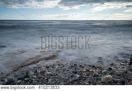 Seawaves Splashing To The Coast With Pebbles Against Stormy Dramatic Cloudy Sky. Wintertime, Longexp