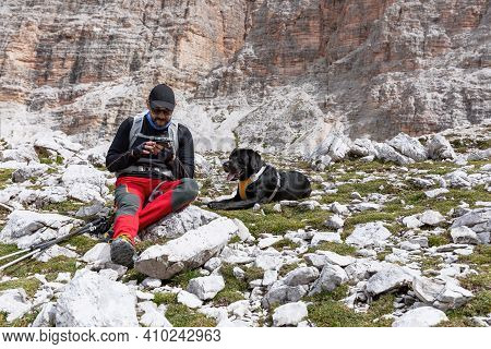 Hiker With His Dog Are Resting On The Pass And Checks The Map On The Smartphone