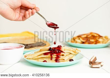 Blini Pancakes With Red Berry Jam Close-up On A Blue Plate On A Light Background . Traditional Russi