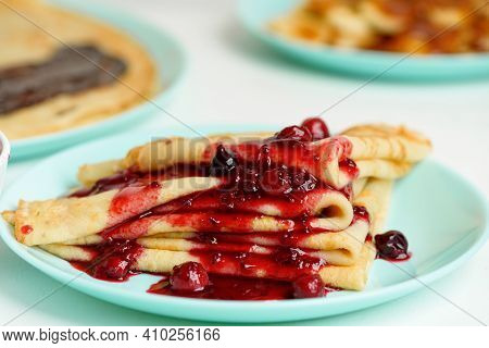 Blini Pancakes With Red Berry Jam Close-up On A Blue Plate On A Light Background . Traditional Russi