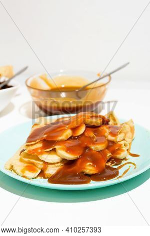 Blini Pancakes With Caramel, Dripping On A Spoon Levitation Close-up On A Blue Plate On A Light Back