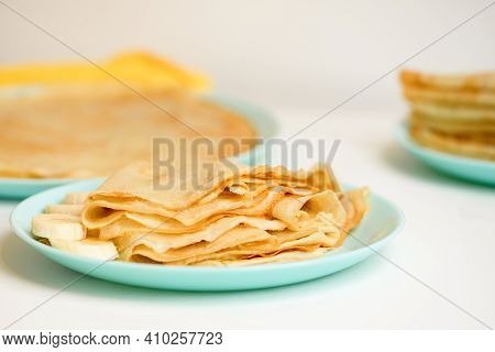 Blini Pancakes With Banana And Caramel, Close-up On A Blue Plate On A Light Background . Traditional