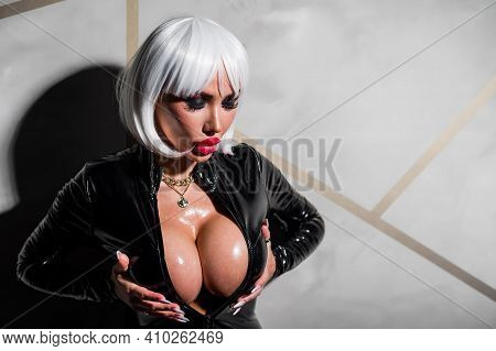 Sexy Woman In A Blonde Wig And Latex Catsuit. Girl With Big Fake Tits