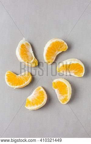Mandarin Slices Laid Out Around In The Shape Of Flower Petals Or Sunlight On A Gray Background