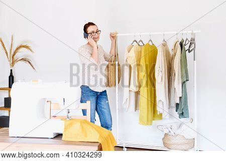 Seamstress Makes The Phone Call In Front Of The Sewing Machine In Small Fashion Studio. Fashion Atel