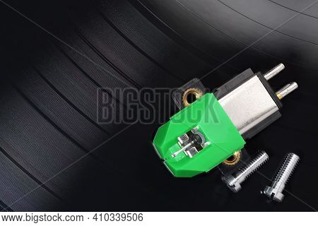 A Magnetic Phono Cartridge And Screws On Vinyl Record Disk. Macro Photo.