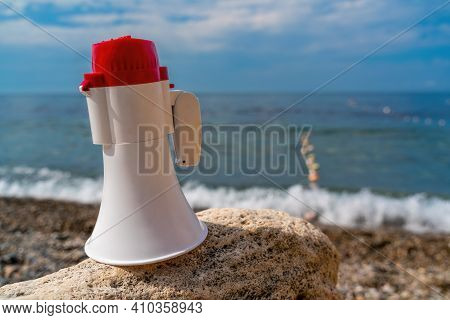Red And White Loudspeaker Or Horn Megaphone For Important Public Information Against Blue Sea At Bea